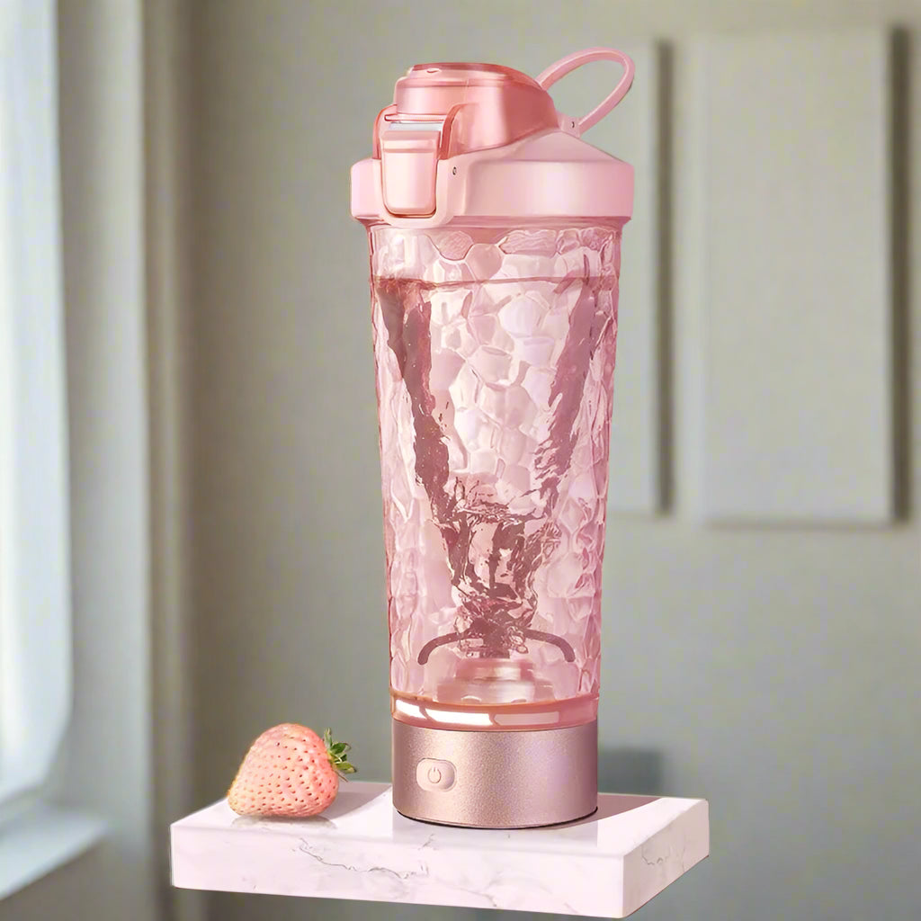 A pink 700 ml electric protein shaker showing a visible vortex while blending a drink.