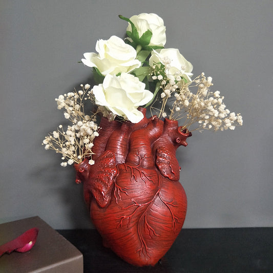 Red heart-shaped resin planter vase holding white flowers for indoor décor