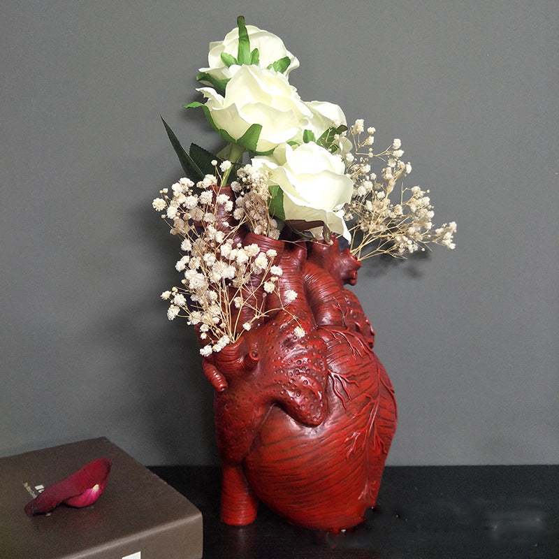 Red heart-shaped resin planter indoor vase with floral arrangement side angle
