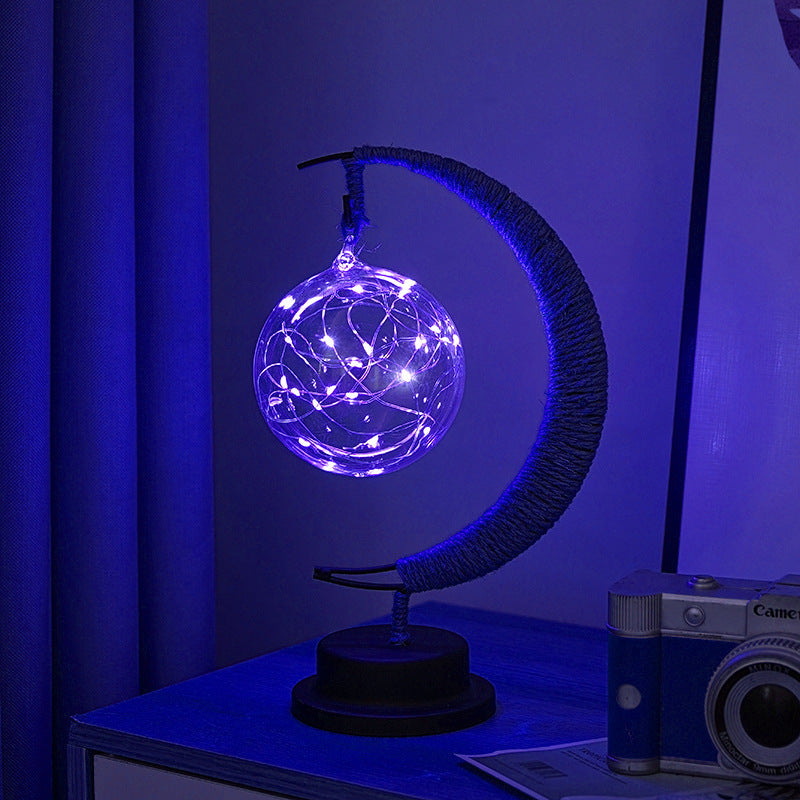 Moon-shaped glass night light with globe illuminated in soft blue glow
