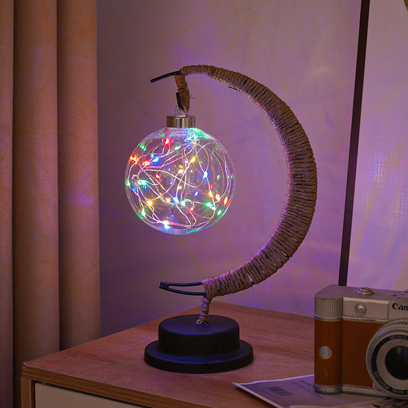 Moon-shaped glass night light with globe glowing in purple light