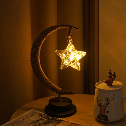 Moon-shaped glass night light with hanging star illuminated in warm golden glow