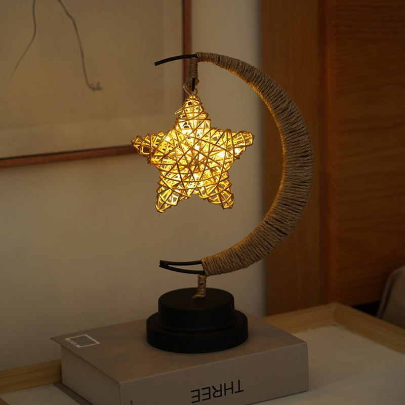 Moon-shaped glass night light with hanging star illuminated in warm indoor light close-up