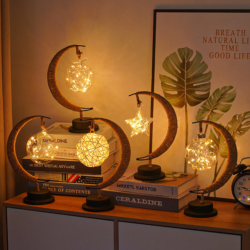 Multiple moon-shaped glass night lights with star and globe designs on shelf display