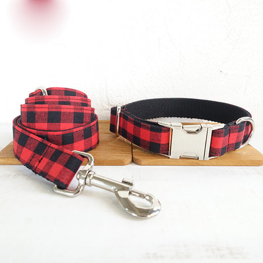 Red and black grid dog collar with matching leash, displayed together on wooden stand