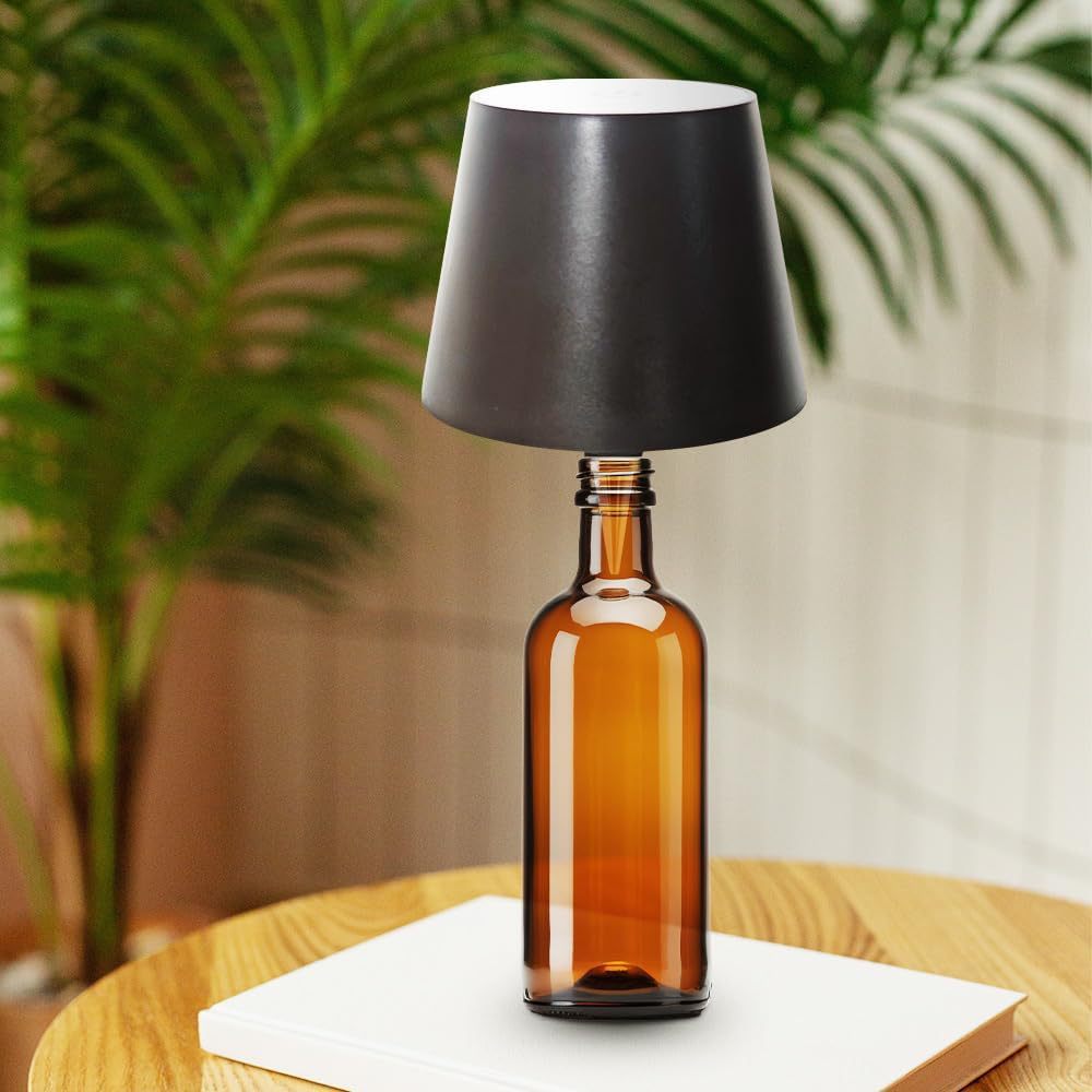 Black wine bottle cap desk lamp on a brown bottle displayed on wooden table